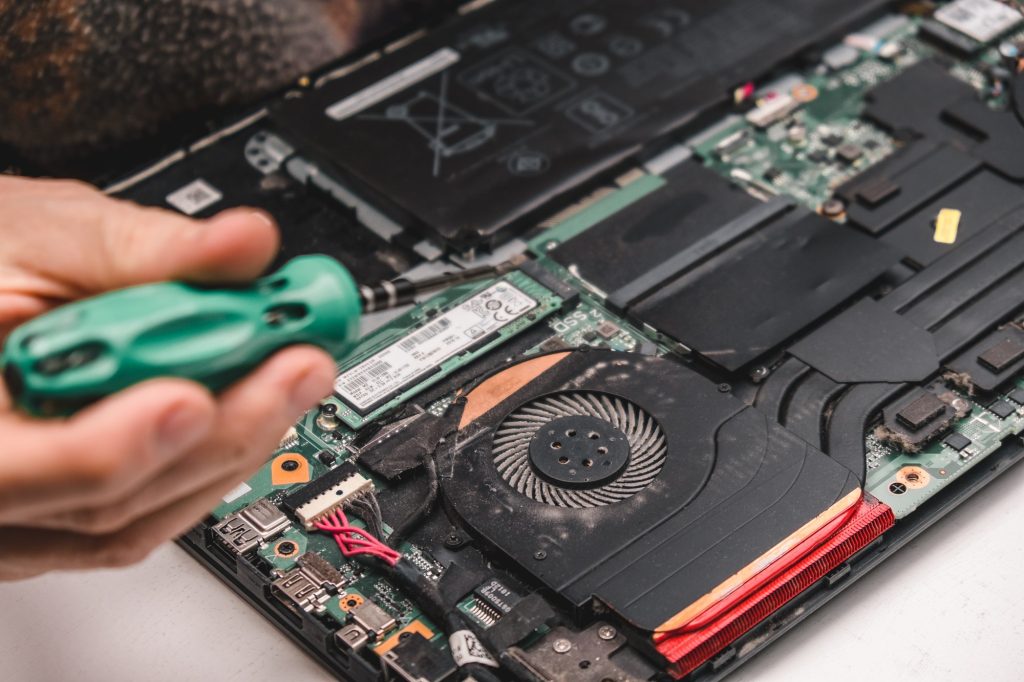 A computer repair specialist disassembles and cleans the laptop cooling system. Laptop maintenance.